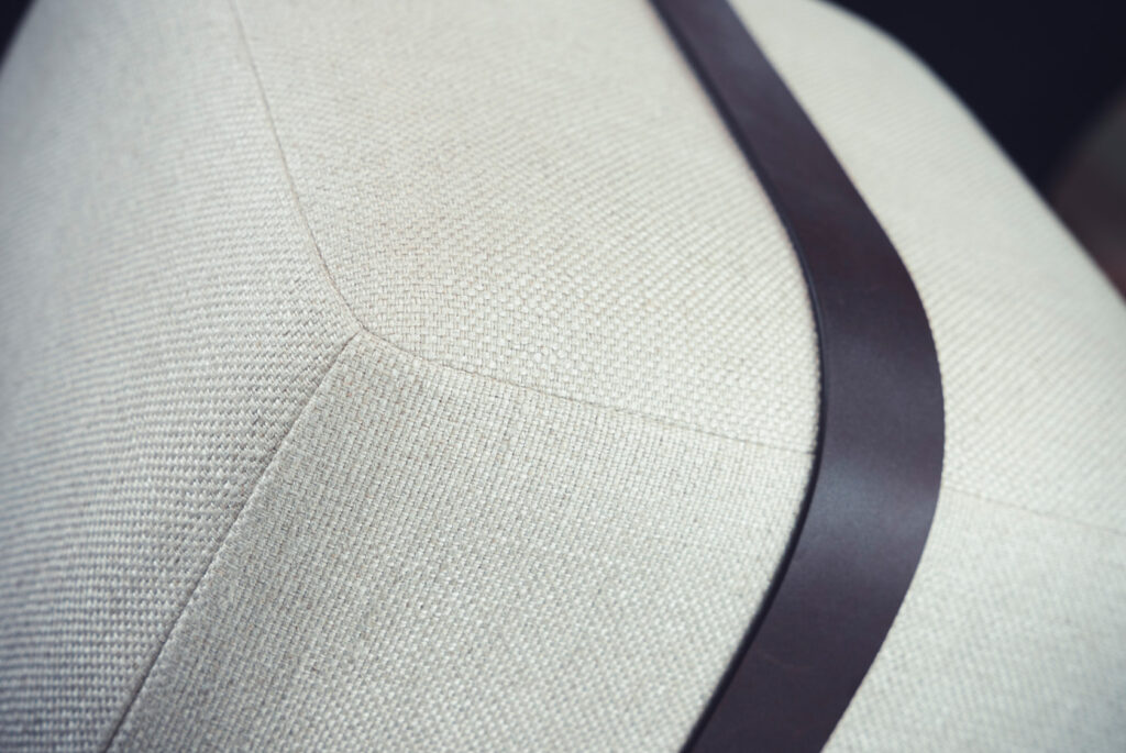 Fabric upholstery covering with leather strap